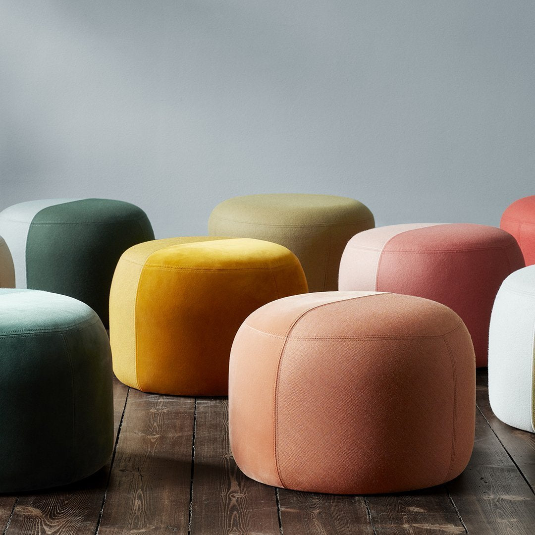 Colorful round ottomans in green, yellow, pink, peach, and white with soft, textured patterns on a wooden floor.