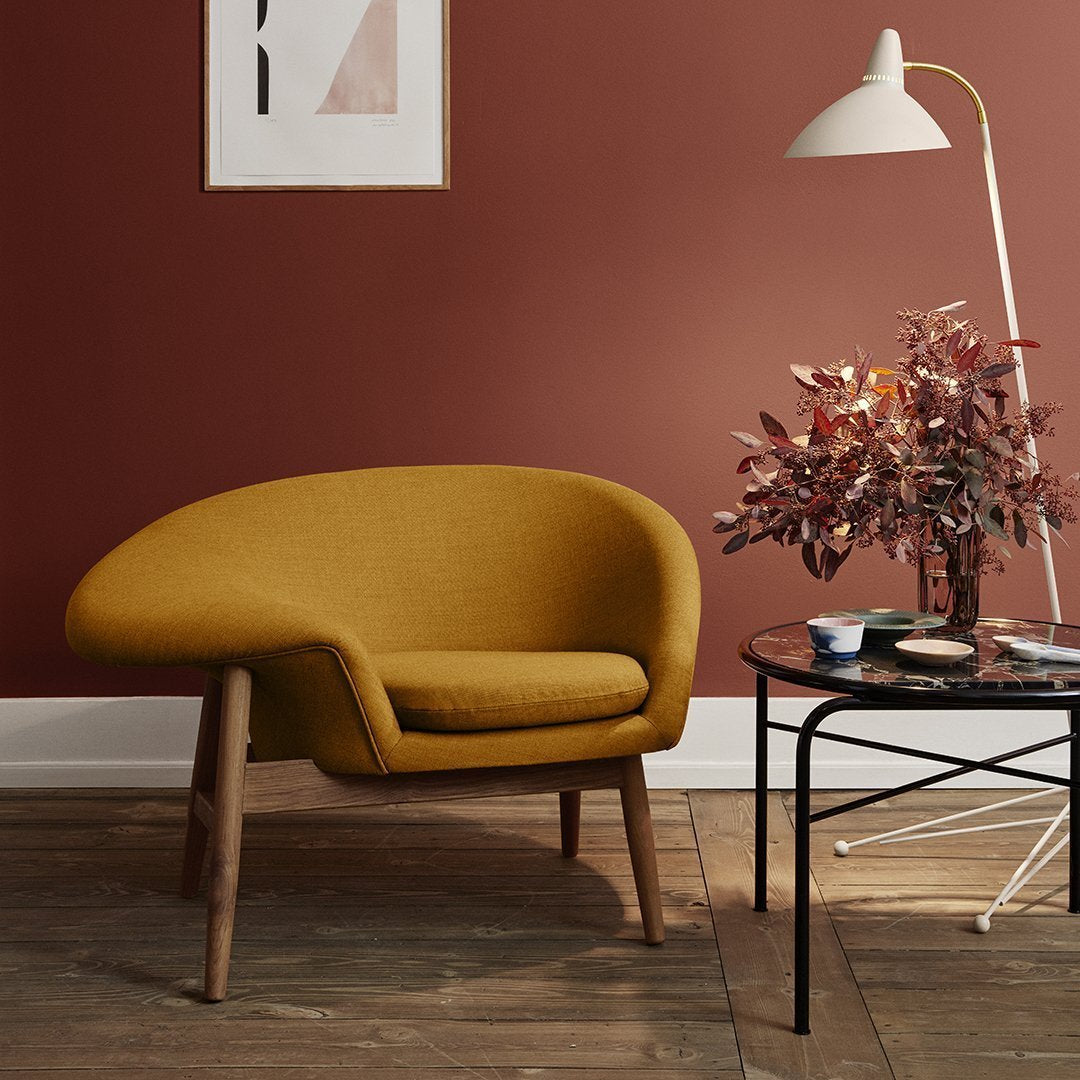 Stylish mustard yellow chair with a smooth texture against a warm terracotta wall, complemented by natural wood and modern accents.