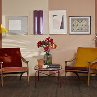 Colorful armchairs in burnt orange and mustard yellow with patterned wall art and a floral centerpiece.