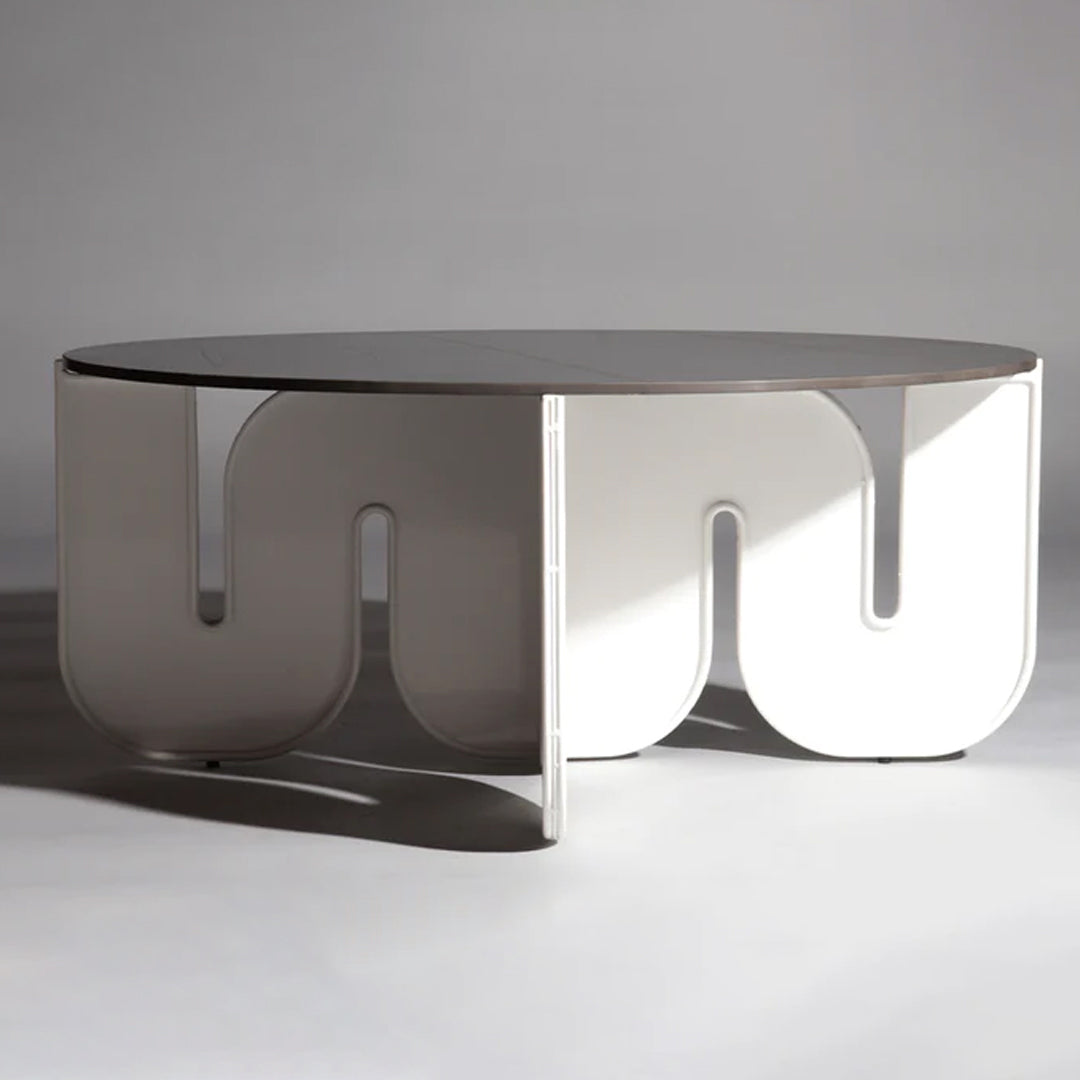 Modern round coffee table with a glossy white finish and unique curved cutout pattern. Ideal for contemporary decor.