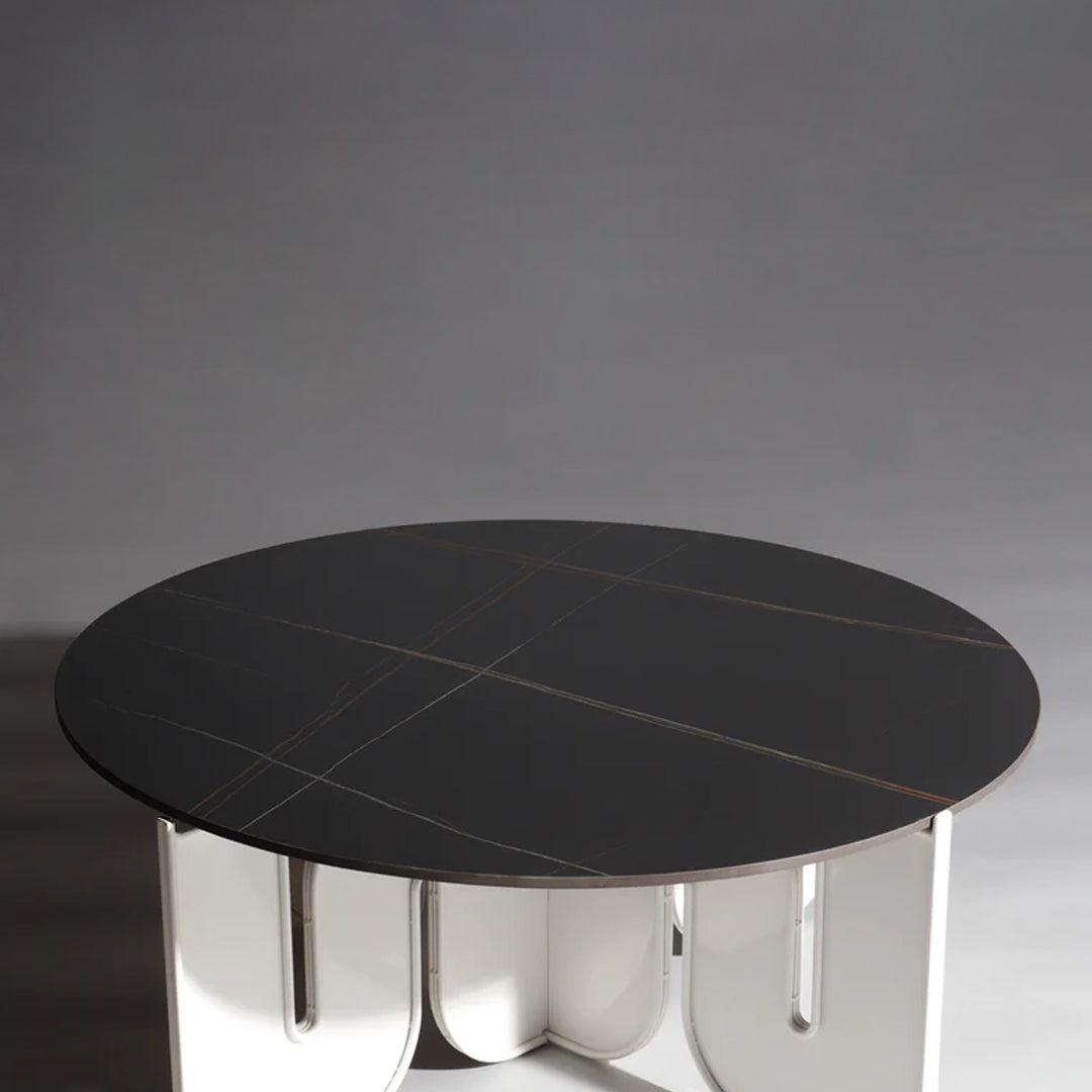 Black round table with subtle gold lines and a sleek white base, creating a modern, elegant design.