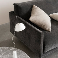 Soft gray sofa with textured charcoal fabric and beige accent pillows, complemented by a minimalist white lamp and marble table.