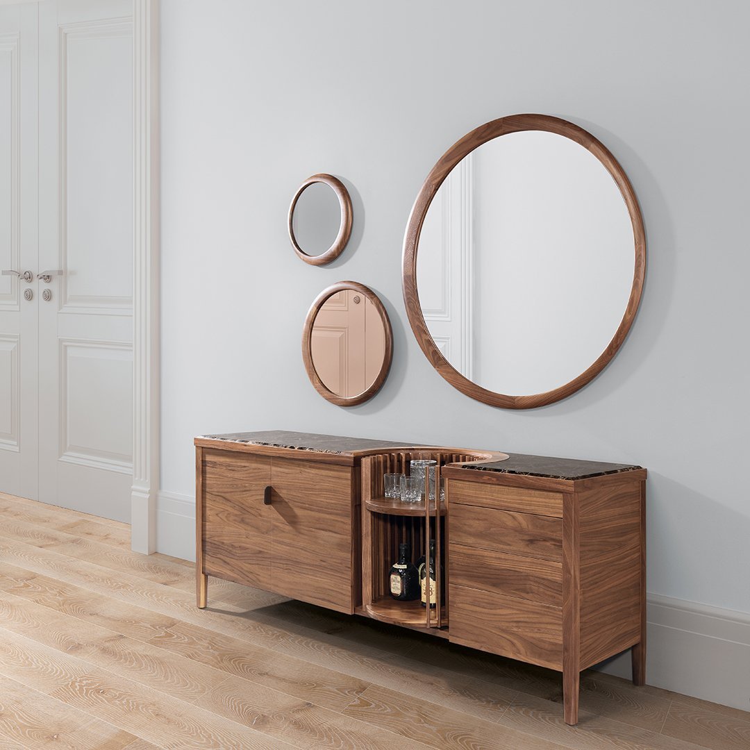 Modern wooden sideboard with a natural finish, complemented by sleek round mirrors in bronze and soft beige tones.