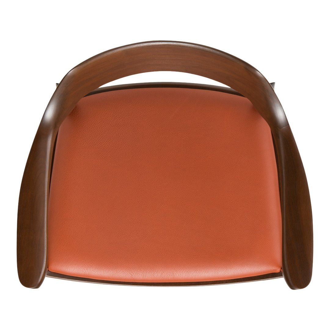 Brown wooden chair with a smooth, orange leather seat and curved armrests. Stylish and modern design.