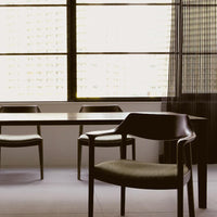 Elegant black dining chair with a subtle textured fabric and a sleek wooden frame, set against a minimalistic backdrop.