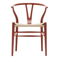 Rust red wooden chair with a woven natural fiber seat and a minimalist design. Perfect for modern decor.