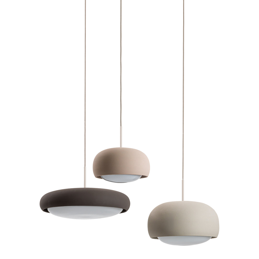 Three modern pendant lamps in beige, light pink, and dark brown with smooth, rounded designs and white shades.