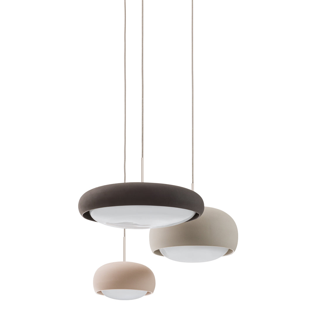 Three modern pendant lights in soft beige, muted brown, and light gray, featuring smooth, rounded shapes.