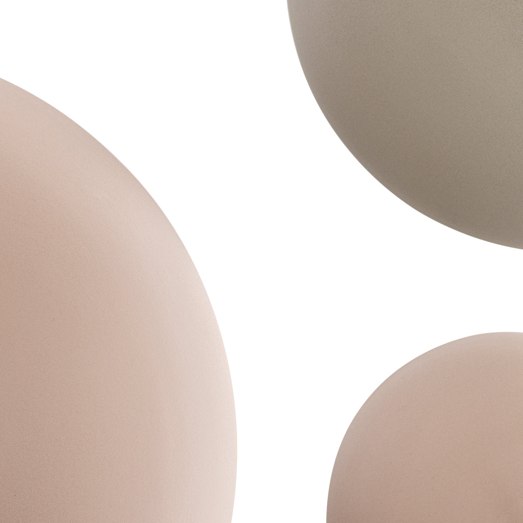 Neutral-colored spheres in soft beige and taupe hues against a white background, highlighting smooth textures.