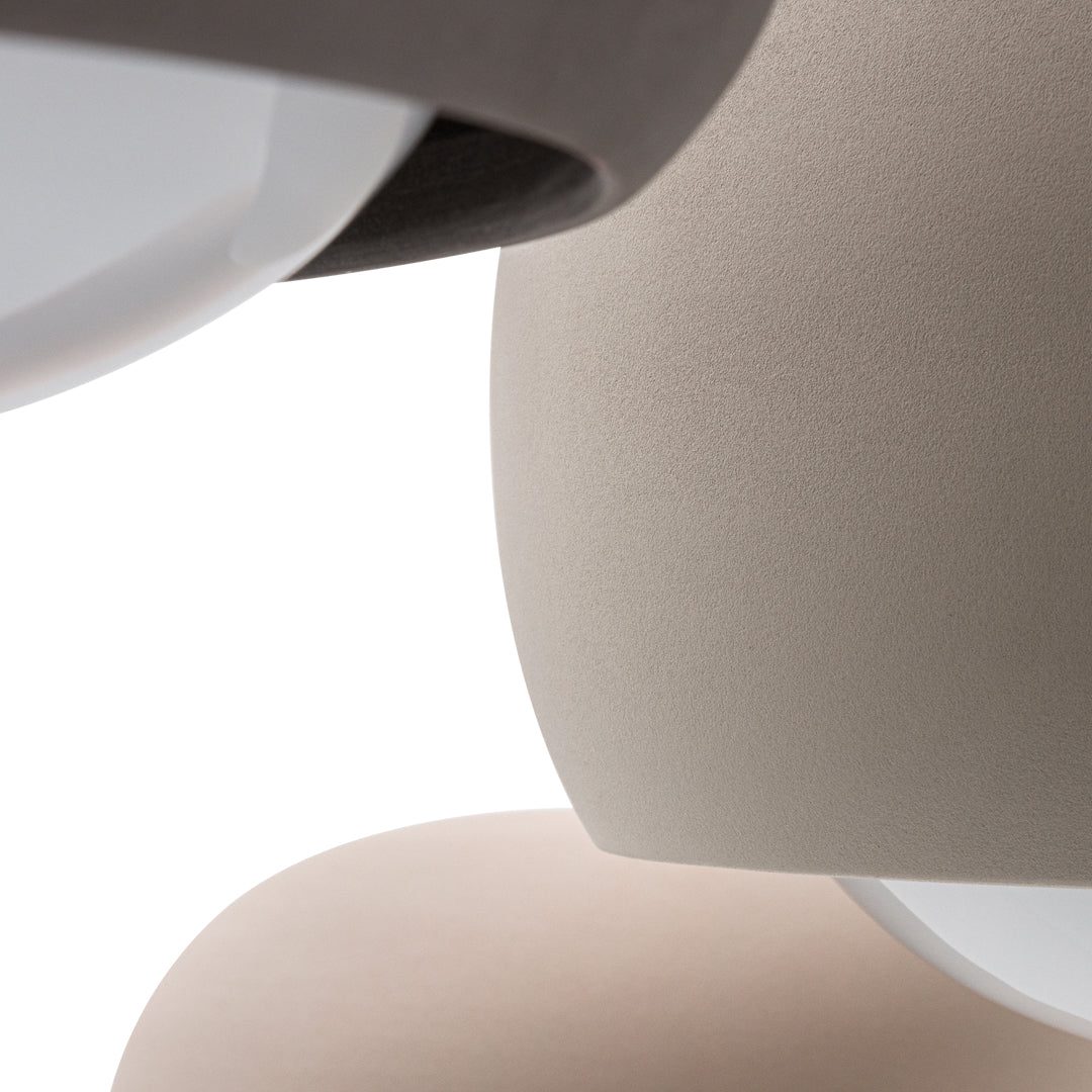 Close-up of textured lamp shades in soft beige and taupe hues with smooth, white accents. Modern design elements.