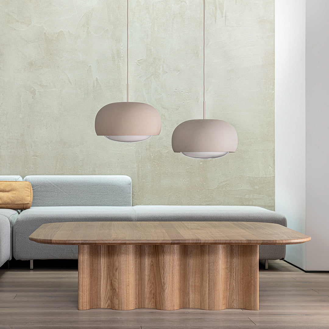 Soft beige pendant lights above a wooden table, complemented by a light gray sofa and neutral textured walls.