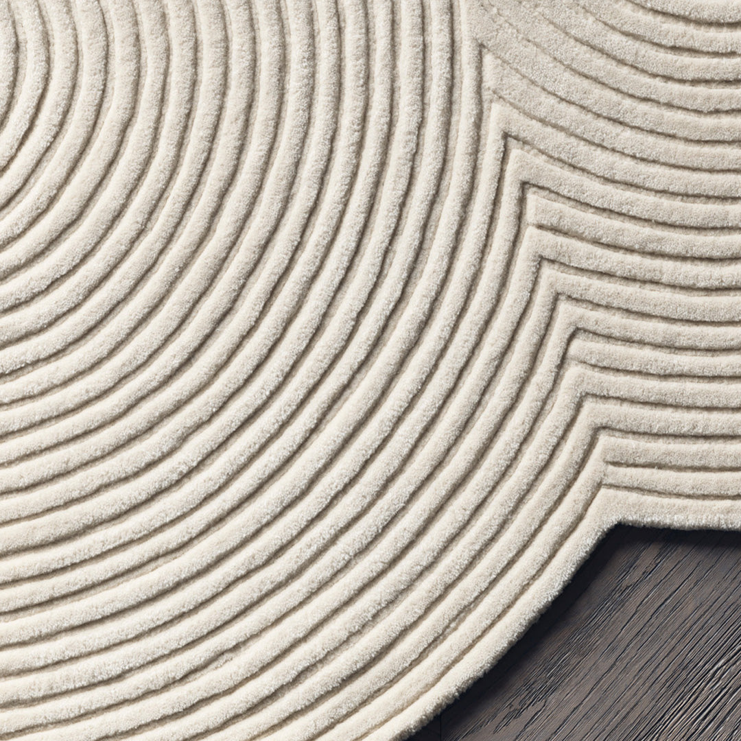Beige textured rug with concentric circular and wave patterns on a dark wooden surface. Perfect for stylish decor.