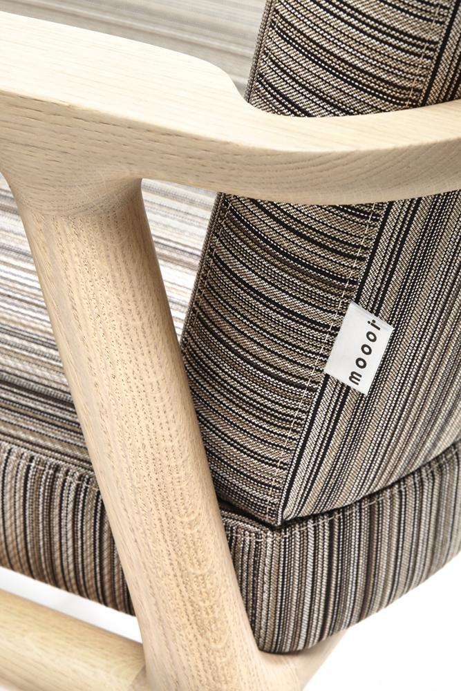 Multicolored striped upholstery with a blend of neutral tones on a modern wooden chair frame.